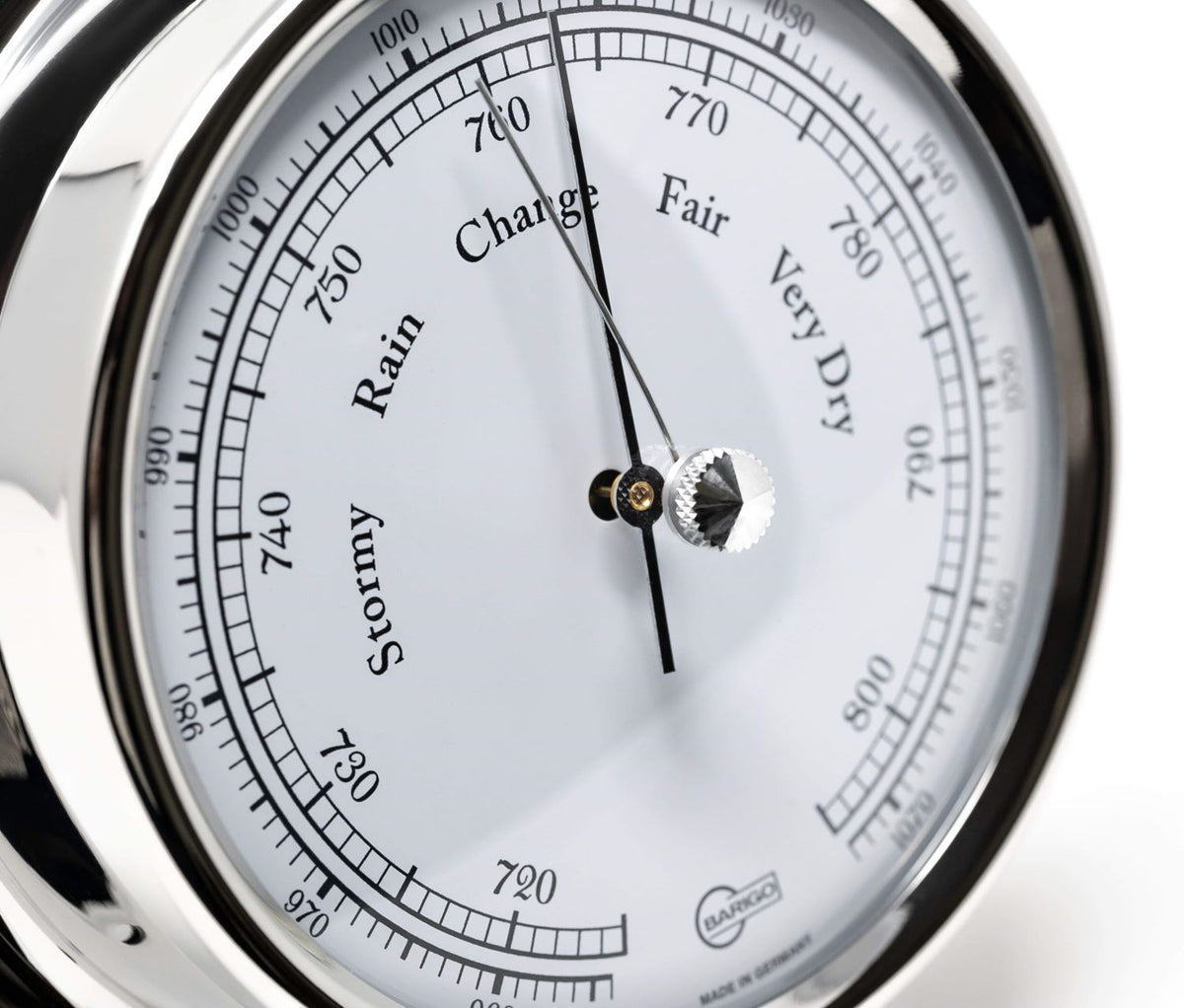 Close-up of German analog barometer with chrome bezel showing weather readings