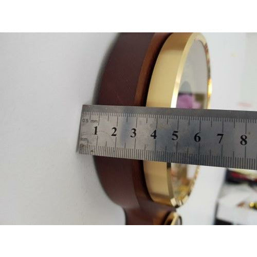 Brass-rimmed wall barometer with wood mount, measured by metal ruler for depth.