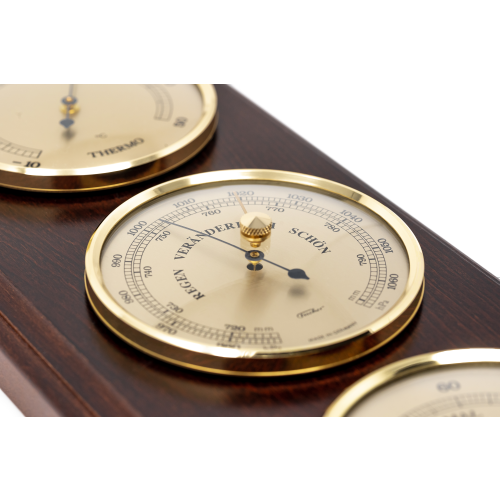 German made analog barometer with gold bezel on wooden mount, close-up view