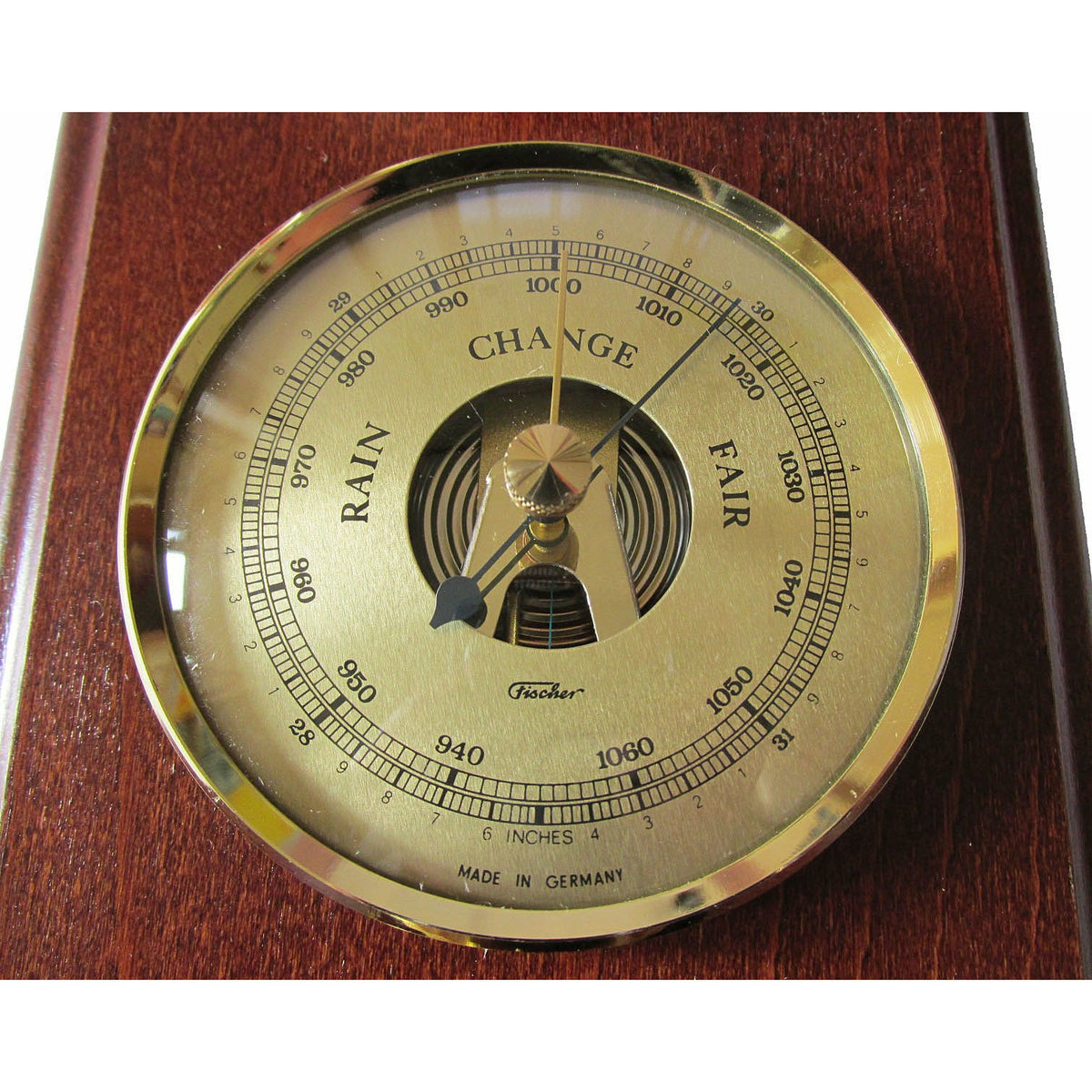Classic analog barometer with gold face and wood mount, showing pressure and weather changes